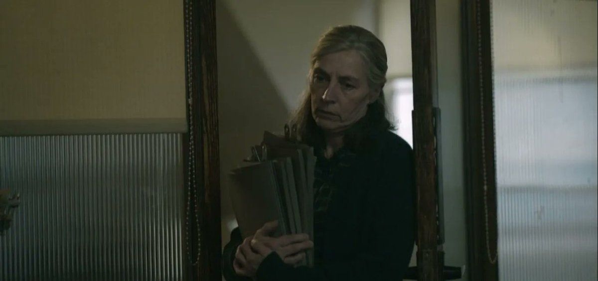 Catherine Standish from Slow Horses entering the room. She holds a few file binders to her chest.