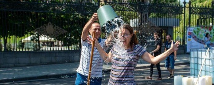 A man drenching a woman with a bucket of water during a cultural celebration of Vardavar in Armenia.